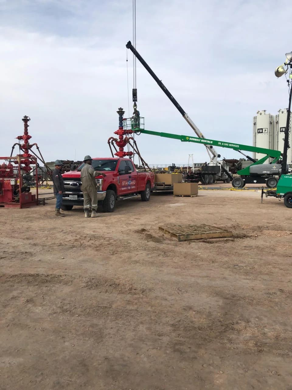 Field crew working near a wellhead with a crane