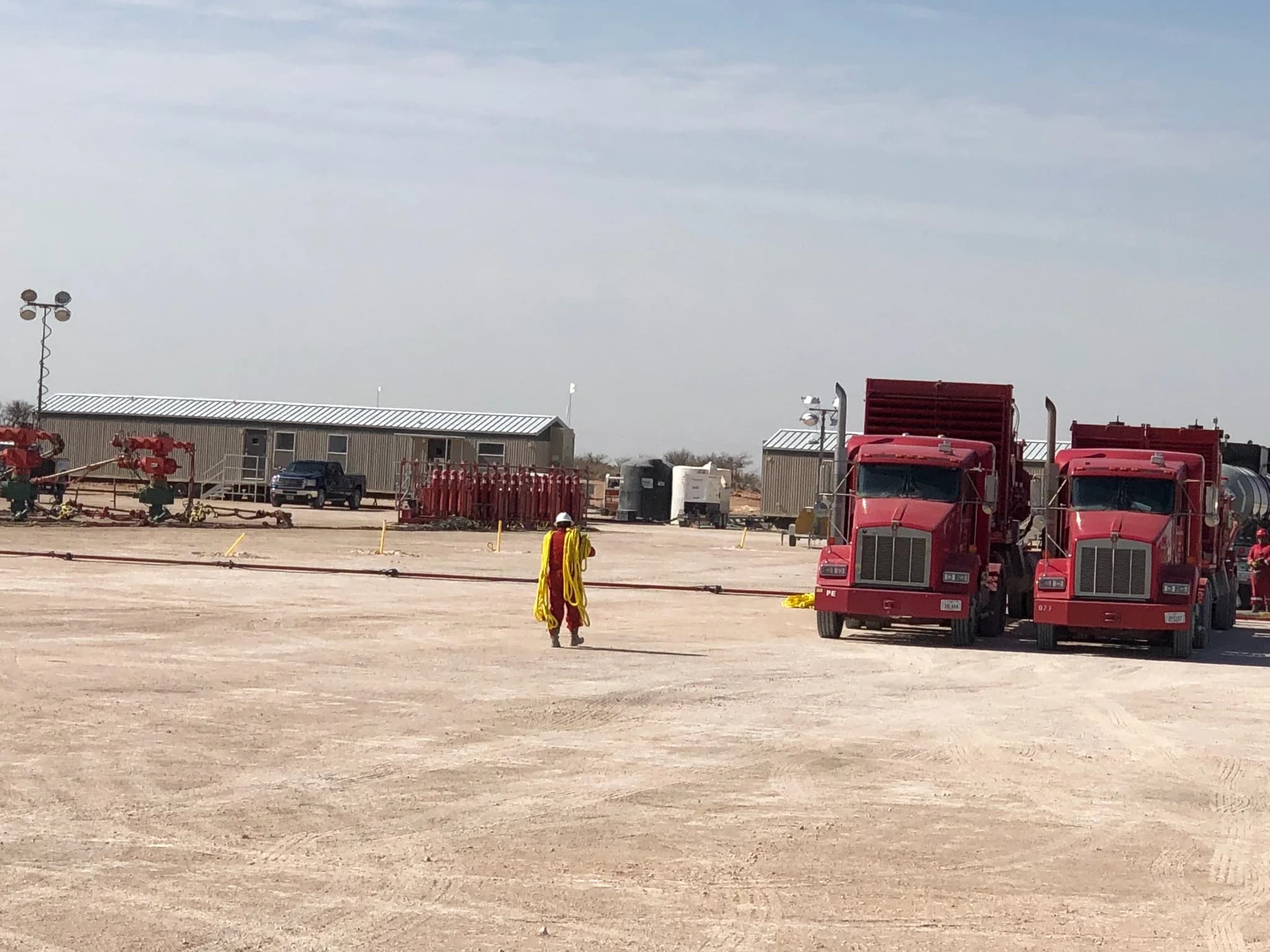 Worker walking across a job site with service trucks